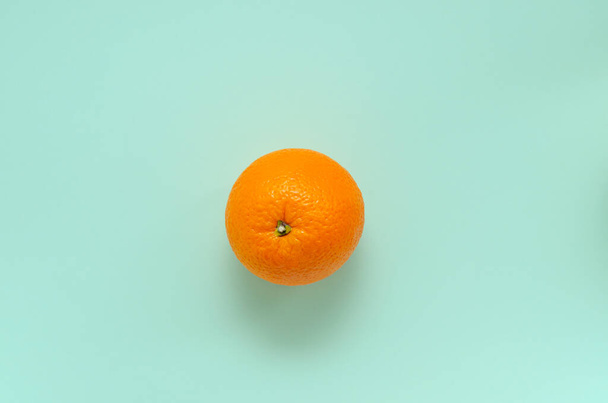 Sweet ripe juicy fresh orange on a mint background. One whole orange fruit. citrus healthy food, vitamin c. with place for text - Fotó, kép