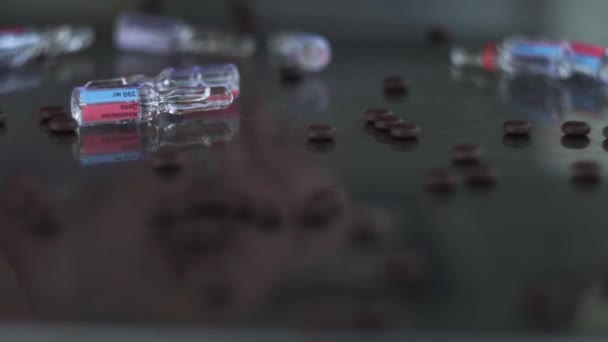 Пальцы с кольцом, собирают рассеянные ампулы на медицинском, металлическом, зеркальном столе, среди коричневых таблеток. Статическая камера
 - Кадры, видео