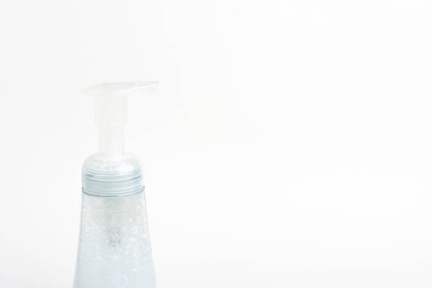 Un'immagine ravvicinata della pompa superiore traslucida e della bottiglia di un dispenser di plastica per sapone espanso su uno sfondo bianco
. - Foto, immagini