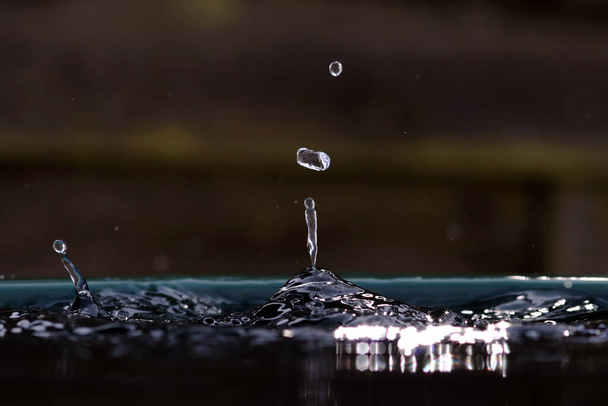 Большая капля дождя падает в бочку с водой
 - Фото, изображение