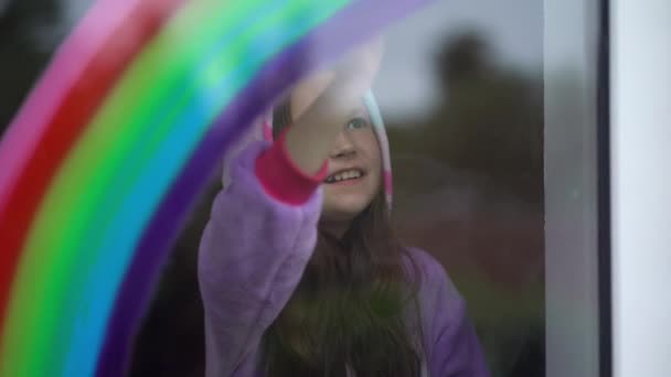 Stay home, flash mob chase the rainbow. girl in pajamas draws the rainbow on the window at home - Imágenes, Vídeo