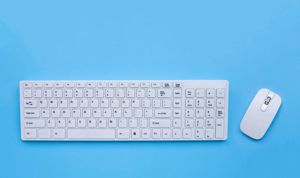 青い背景に白いコンピュータのキーボードとマウス。スペースのコピー - 写真・画像