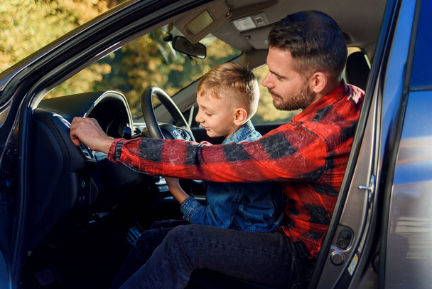 όμορφος πατέρας δείχνει σε κάτι ενώ διδάσκει έφηβος γιος οδήγηση αυτοκινήτου - Φωτογραφία, εικόνα