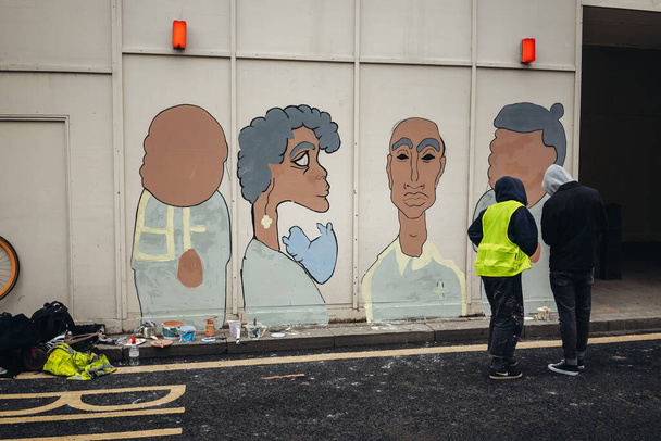 ロンドン/イギリス- 2020年6月6日:ブラックライブスマターがコロナウイルスの大流行に抗議。壁に絵を描く人々 - 写真・画像