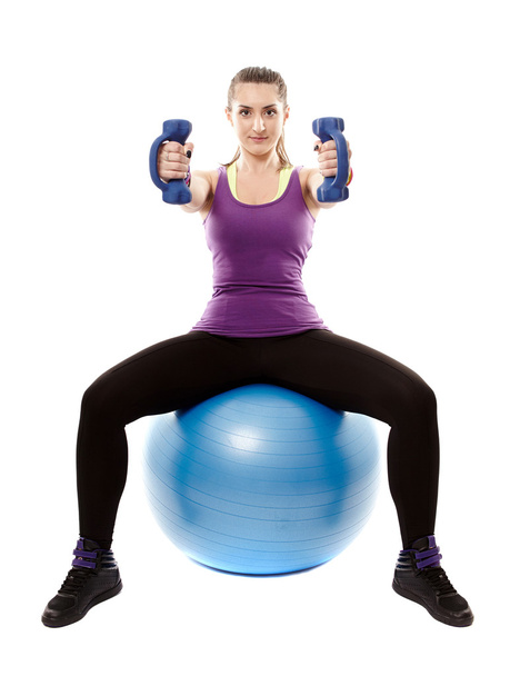 Athletic woman sitting on a ball and working with dumbbells - Φωτογραφία, εικόνα