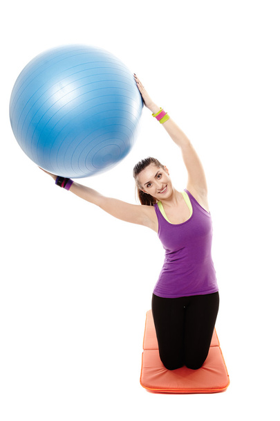 Athletic woman holding a ball and doing stretching - Foto, Imagen