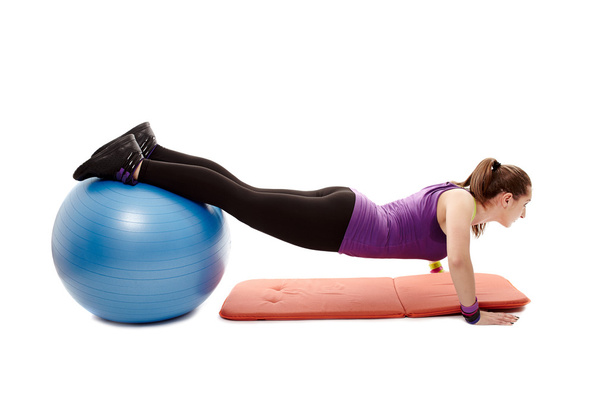 Athletic woman doing pushups with legs on the ball - Photo, Image