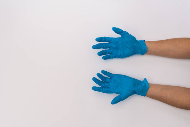 Foto de stock de manos someones con guantes de látex médicos azules sobre un fondo blanco. La persona es irreconocible.
. - Foto, Imagen