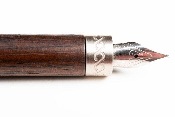 Plan rapproché du canon en bois et pointe d'écriture d'un stylo plume classique sur fond blanc uni
. - Photo, image