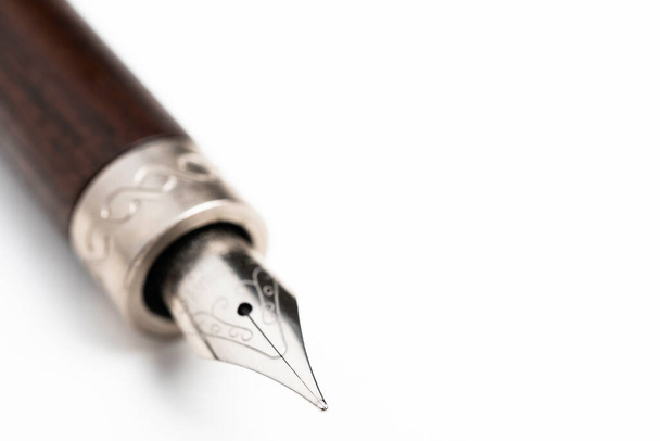 Plan rapproché du canon en bois et pointe d'écriture d'un stylo plume classique sur fond blanc uni
. - Photo, image