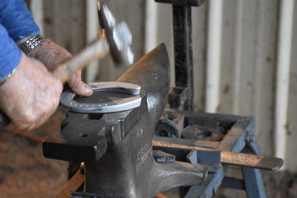 Farrier beating a horseshoe into shape on an anvil. - Photo, Image