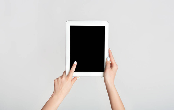 Mano femenina tocando la pantalla en blanco de la tableta sobre fondo blanco, maqueta para su diseño
 - Foto, Imagen