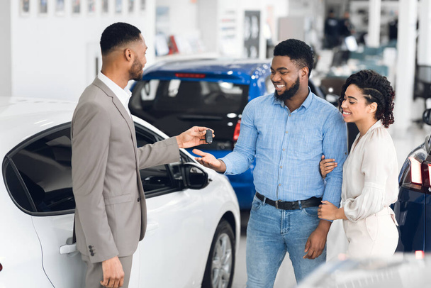 Myyntimies antaa auton avain ostajille Test-Drive in Dealership - Valokuva, kuva