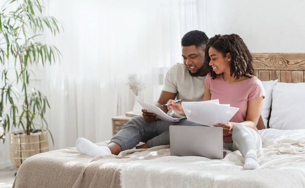 Black man and woman checking on monthly expences together - Photo, image