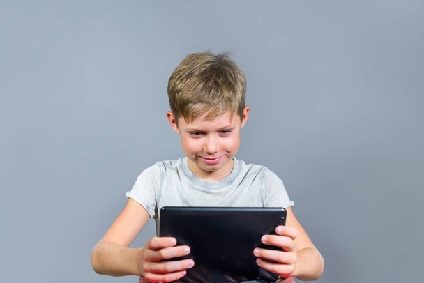 Cute boy is studing online through tablet at home. Remotely study. Distance education. Back to school. Stay at home. Quarantine. Unschooling - Φωτογραφία, εικόνα