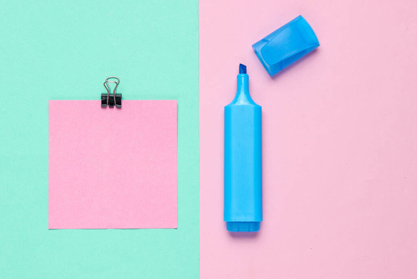 Stationery office supplies. Paper clip, felt-tip pen, memo piece of paper on pink blue pastel the background - Photo, Image