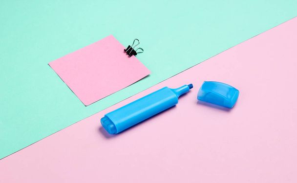 Stationery office supplies. Paper clip, felt-tip pen, memo piece of paper on pink blue pastel the background - Photo, Image