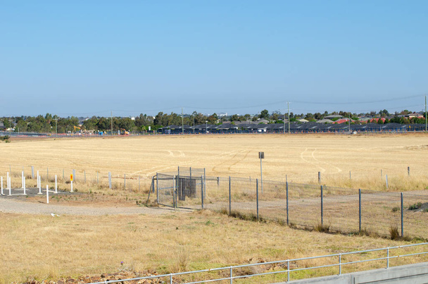 Kilátás a nagy üres föld néhány vadonatúj lakóházak a távolban. Az ingatlanfejlesztés és a lakásépítés fogalma. Tarneit, Melbourne, VIC Ausztrália. - Fotó, kép