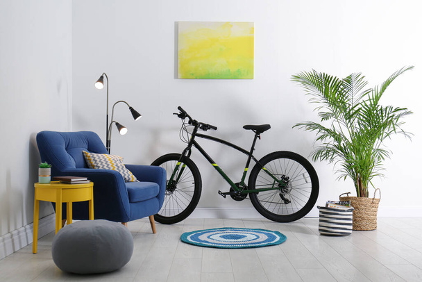 Modern bicycle and comfortable armchair in stylish living room interior - Fotó, kép