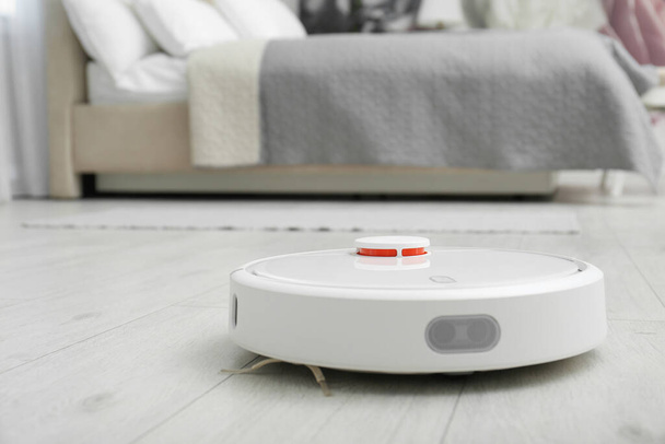 Hoovering floor with modern robotic vacuum cleaner indoors, closeup. Space for text - Foto, Imagem