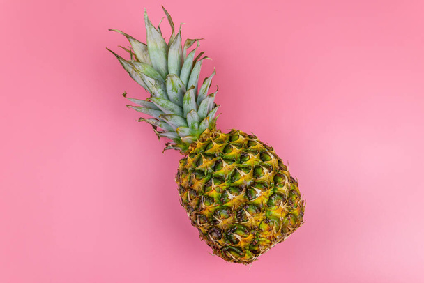 One whole pineapple on pink background. Top view - Zdjęcie, obraz