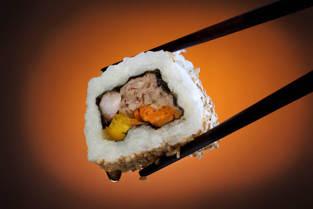 Суши - японское блюдо, состоящее из маленьких шариков или рулонов холодного риса со вкусом уксуса, подаваемого с гарниром из овощей, яиц или сырых морепродуктов
. - Фото, изображение
