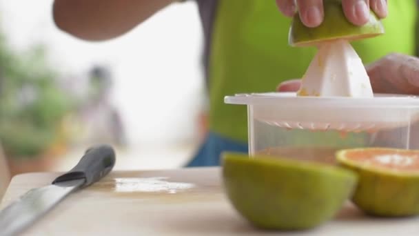Close-up handen van huisvrouw knijpt sinaasappelsap met squeezer tijdens het ontbijt thuis. Zelfgemaakt. Een gezonde levensstijl. Langzame beweging. - Video