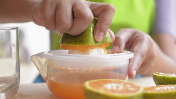 主婦達の手が自宅で朝食を用意しながらオレンジジュースを搾りガラスに注ぎ込む。自家製だ。健康的なライフスタイル。スローモーション。パンニングショット. - 映像、動画
