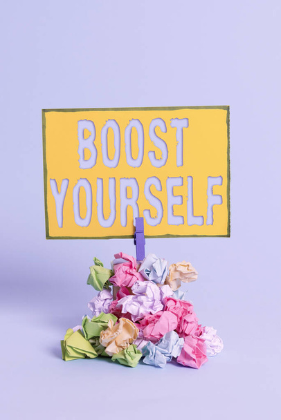 Text sign showing Boost Yourself. Conceptual photo delivering a lift up to someone making them energetic again Reminder pile colored crumpled paper clothespin reminder blue background. - Photo, Image