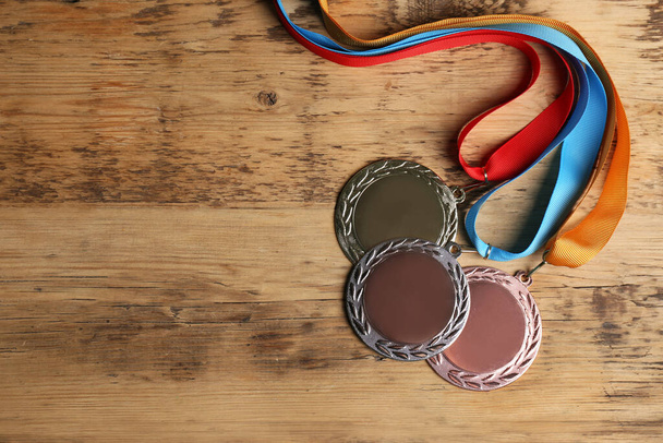 Gold, silver and bronze medals on wooden background, flat lay. Space for design - Photo, Image