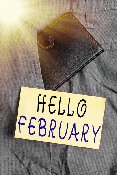 Γραπτό σημείωμα που δείχνει Hello Φεβρουάριος. Επαγγελματική φωτογραφία showcasing χαιρετισμό που χρησιμοποιείται κατά την υποδοχή του δεύτερου μήνα του έτους Μικρό πορτοφόλι στην μπροστινή τσέπη του παντελονιού κοντά σε χαρτί σημειώσεων. - Φωτογραφία, εικόνα