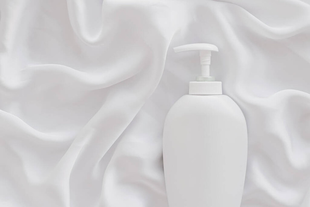 Blank label cosmetic container bottle as product mockup on white silk background - Foto, afbeelding
