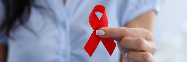 Jeune femme tient ruban rouge symbole lutte contre le cancer
 - Photo, image