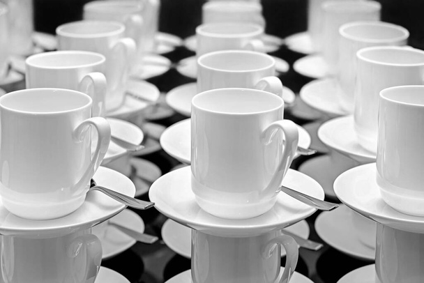 Vzor ze skupiny prázdných bílých pohárků a talířků s lžičkou. Mnoho řad bílých šálků čaje, stojící na sobě, pro podávání snídaně nebo bufetu na semináři. Tapeta - Fotografie, Obrázek