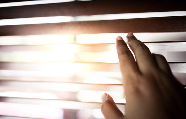 Ανοίγοντας το χέρι Sunblind μέσα στο σπίτι. Ηλιακό φως μέσα από το παράθυρο - Φωτογραφία, εικόνα