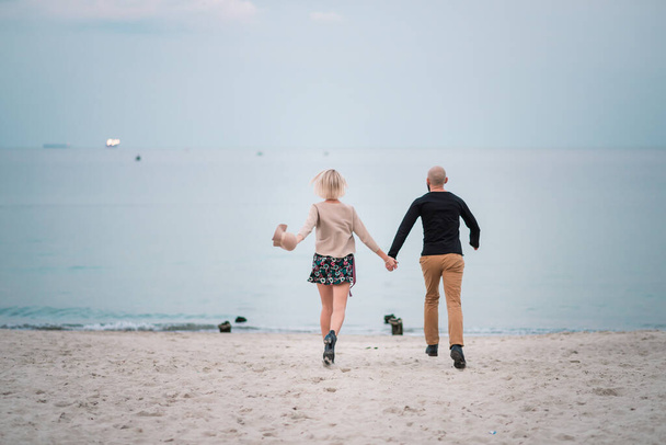 glückliches junges Paar hat Spaß am Strand, Händchen haltend. - Foto, Bild