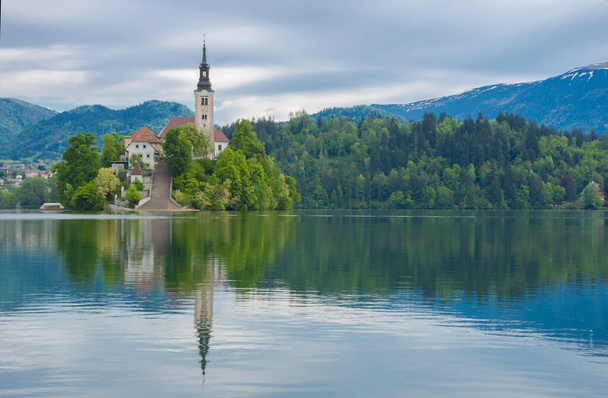 Gyönyörű reggel a Bled tónál és Julian Alpokban a háttérben. A tó sziget és bájos kis templom szentelt Nagyboldogasszony híres turisztikai attrakció Szlovéniában - Fotó, kép