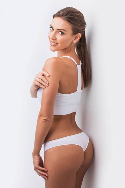 Young beautiful woman in white cotton underwear touching own skin standing , white background - Fotó, kép