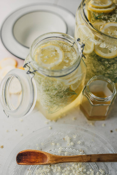 potten zelfgemaakte zomerdrank, gemaakt van natuurlijke gisting van vlierbloesem in citroen en honingsiroop. Roemeense traditionele socata sap, bekend als een natuurlijke remedie. Een gezonde levensstijl. Sluiten. - Foto, afbeelding