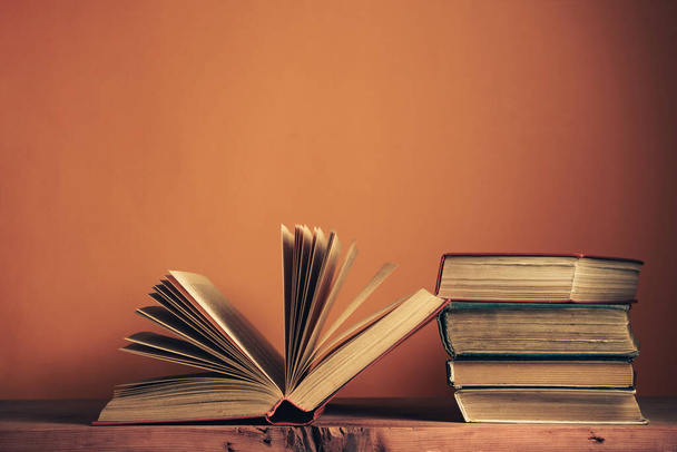 Régi könyvek egy régi fából készült asztalon. Gyönyörű narancs fal háttér. - Fotó, kép