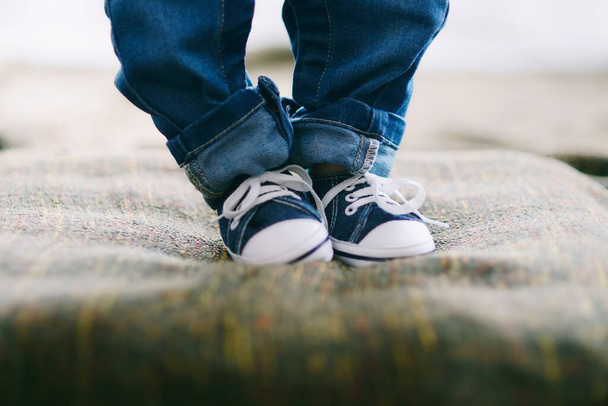 Detail photo of baby with sneakers and jeans learning to walk. - Photo, image