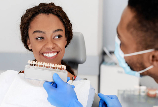 Dentista aplicando amostras de escala de dente definido como paciente sorridente
 - Foto, Imagem