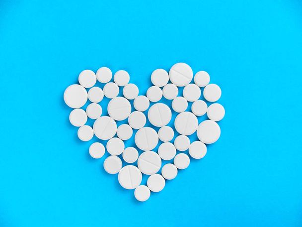 Fehér gyógyszer tabletták alakú szív egy kék háttér felülnézet másolási hely. - Fotó, kép