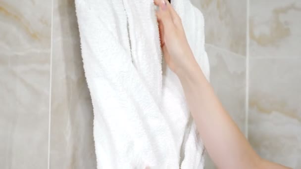 Housekeeper adjusting white bathrobe in hotel bathroom. Cleaning service. Close-up. Apartament is ready for guests. bathrobes hanging. Large bathroom in residential building. 4 k video - Footage, Video