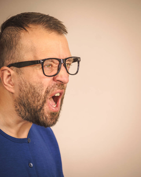 Adult man wearing eyeglasses yelling at somebody. Side profile view with copy space - Фото, зображення