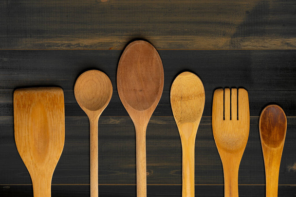 Cucharas de madera, tenedor y agitador sobre mesa de madera oscura. Concepto de cocina y cocina
. - Foto, imagen