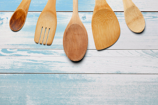Cucchiai di legno, forchetta e agitatore su tavolo di legno turchese. Cucina e concetto di cottura
. - Foto, immagini