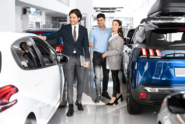 Продавец предлагает пару новых автомобилей, стоящих в офисе
 - Фото, изображение