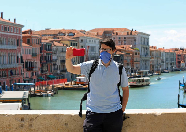 Nuori mies, jolla on sininen kirurginen naamio Rialton sillalla Venetsiassa Italiassa - Valokuva, kuva