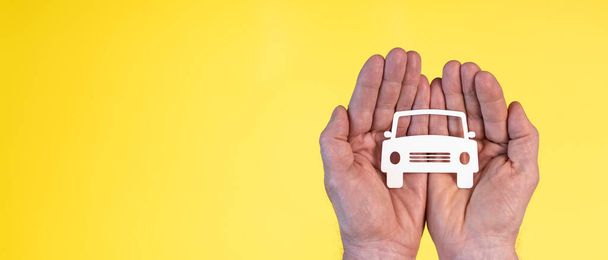 Konzept der Autoversicherung mit Papierauto in der Hand auf gelbem Hintergrund - Foto, Bild